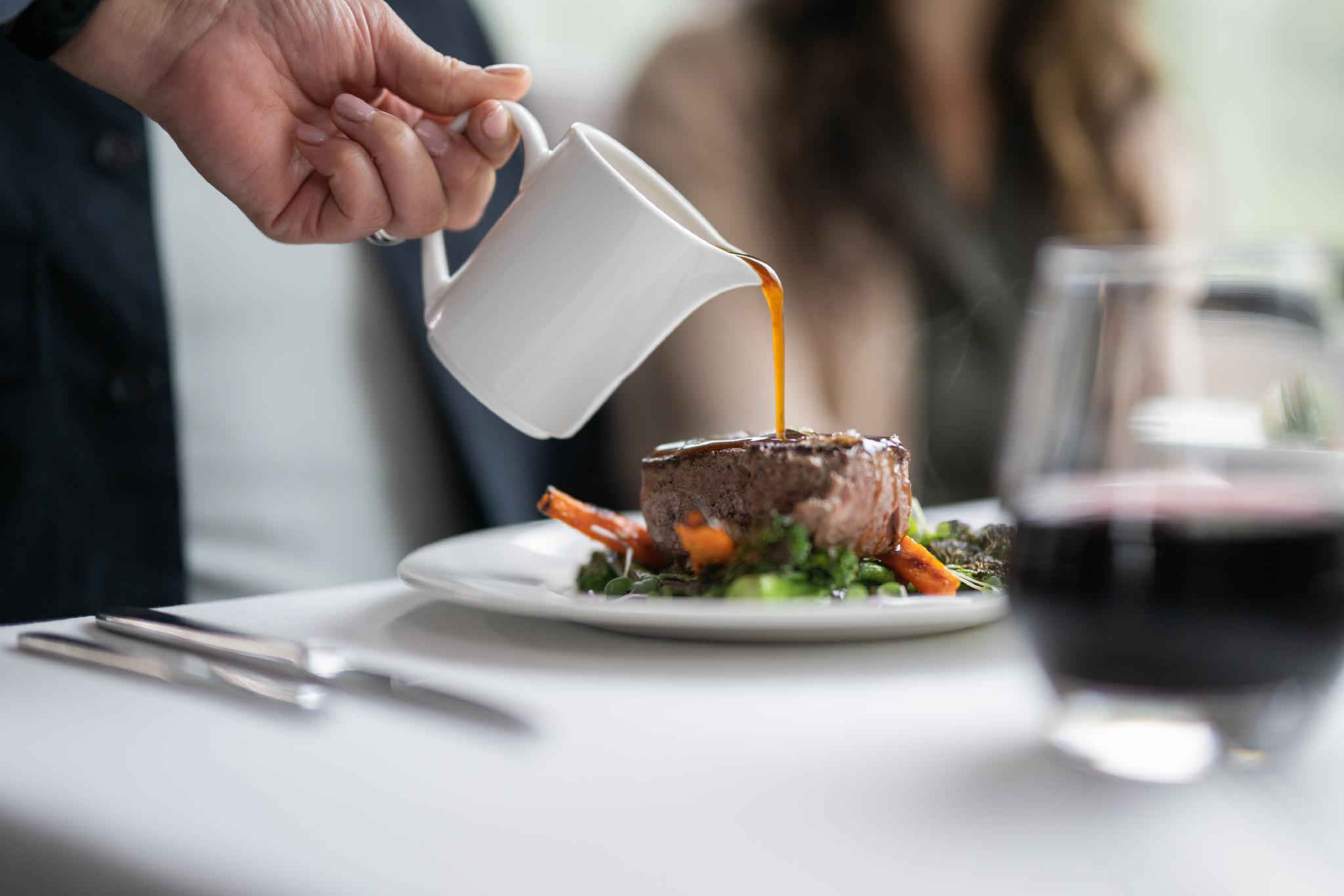 Rocky Mountaineer chef pouring sauce over a gourmet dish